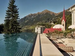 Pool with red church tower and mountain in the background.