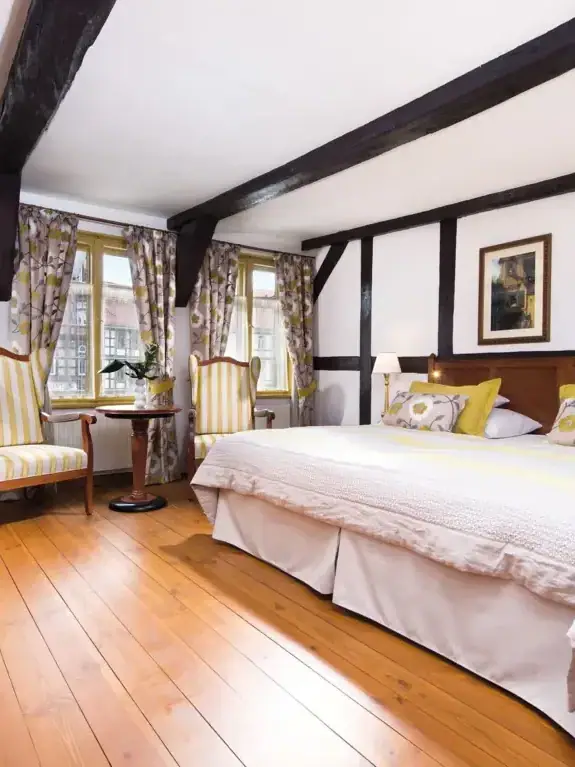 A room with a bed and some chairs.
