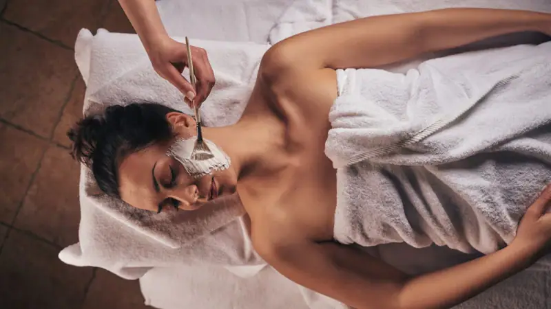 A woman lying down with a facial mask on her face.