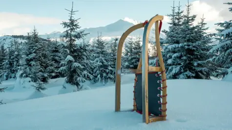 A sledge stands in a snowy winter landscape and mountains can be seen in the background.