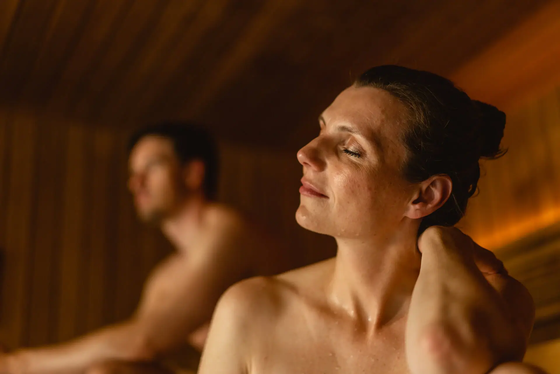 Eine Frau mit geschlossenen Augen in einer Sauna.