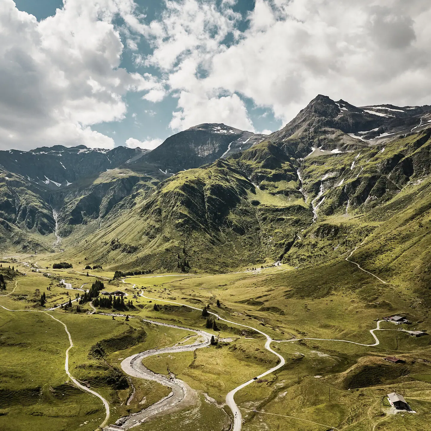 A winding road through a valley with mountains in the background.