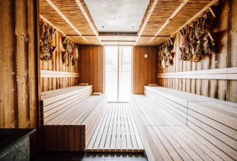 A wooden sauna with bundles of herbs hanging from the walls. 