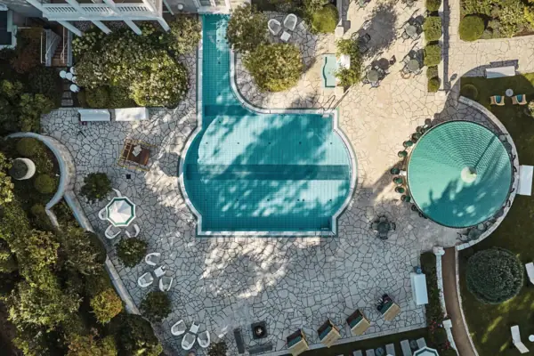 Swimming pool with a fountain and chairs at the Heringsdorf Wellness Hotel