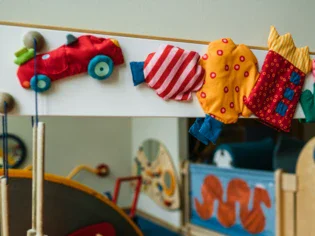 A children's play area with small fabric imitations of toys and food hanging on the wall. Further decoration and toys can be seen in the background. 