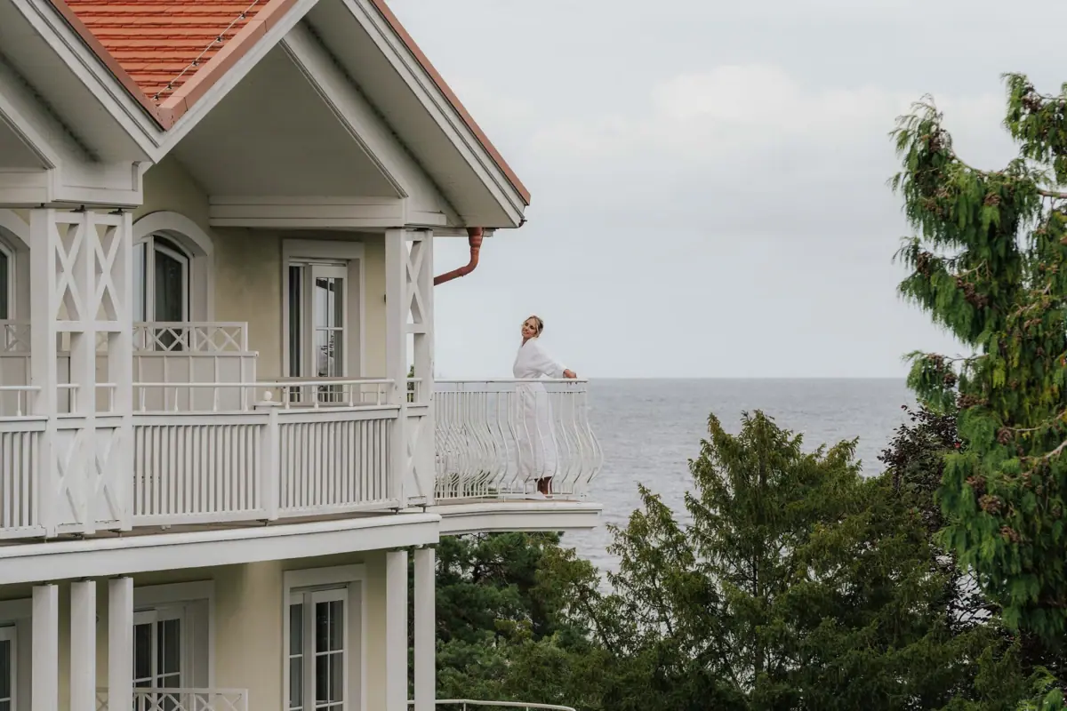 A woman is standing on a balcony overlooking a body of water.