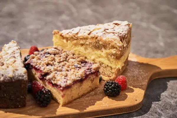 A slice of cake with berries on a wooden board.