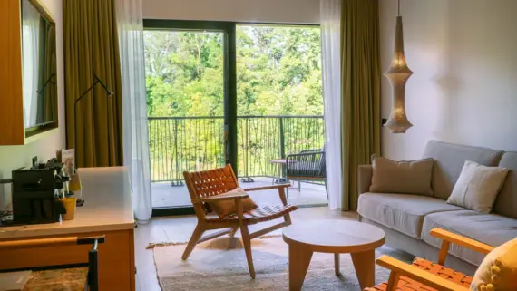 Elegantly designed living room with sofa, armchair and coffee table near a window with a view of the greenery.