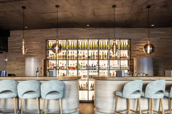 Bar with chairs and shelves full of bottles in an interior room.