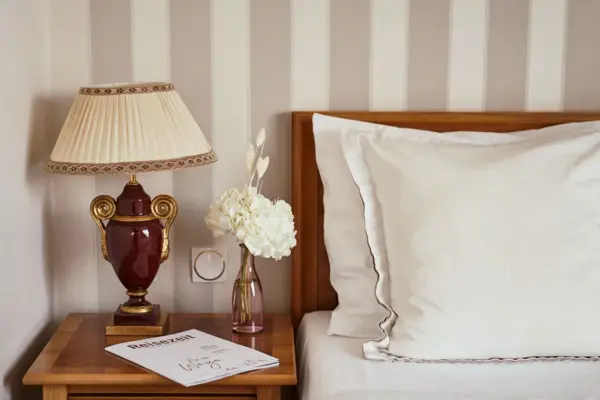 A lamp on a bedside table next to a bed.