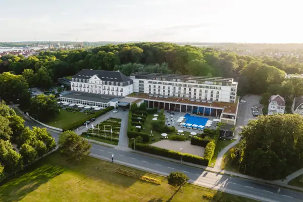 A large white building with a pool and trees.