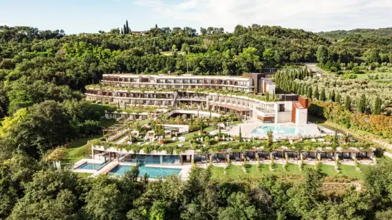 Aerial view of a resort surrounded by lush vegetation, trees and grassy areas.