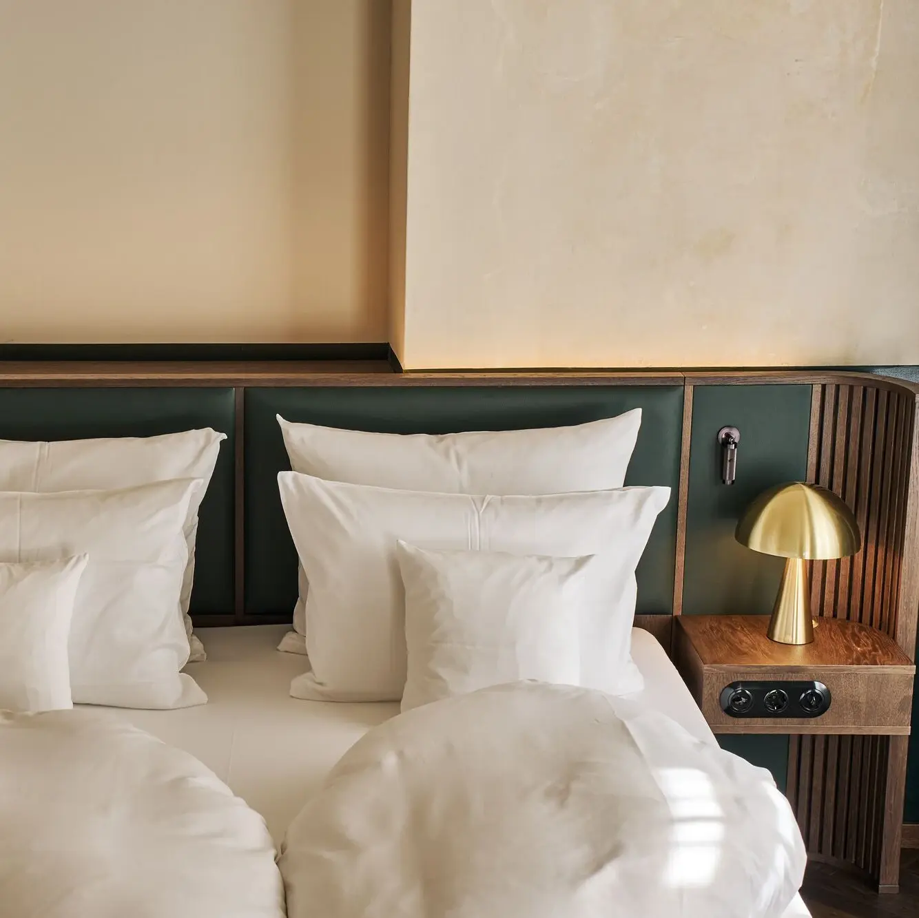 A bed with white pillows and a green headboard.