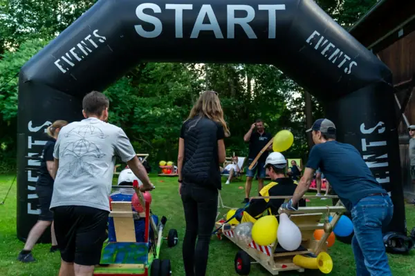 A group of people in a field with a black archway.