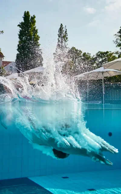 Person jumps into an outdoor pool.