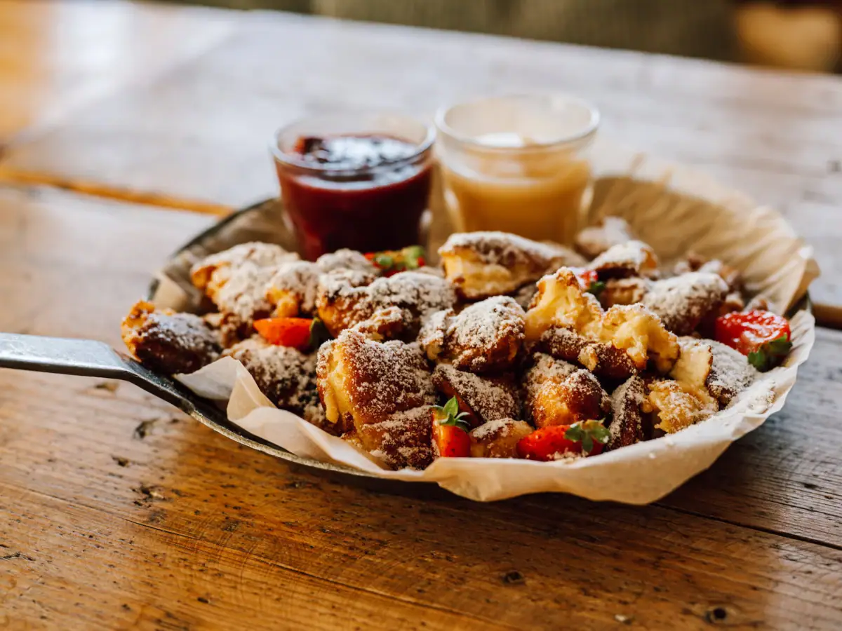 Kaiserschmarrn A plate of food with two glasses of jam on a table.