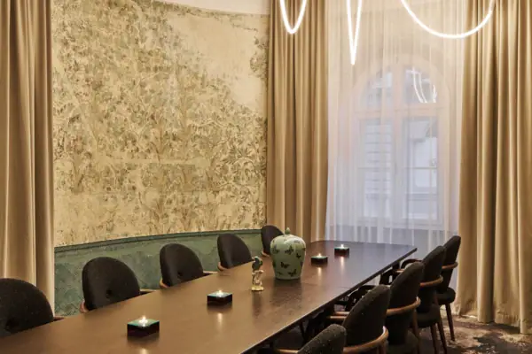 A room featuring a table and chairs with a window and curtains in the background.