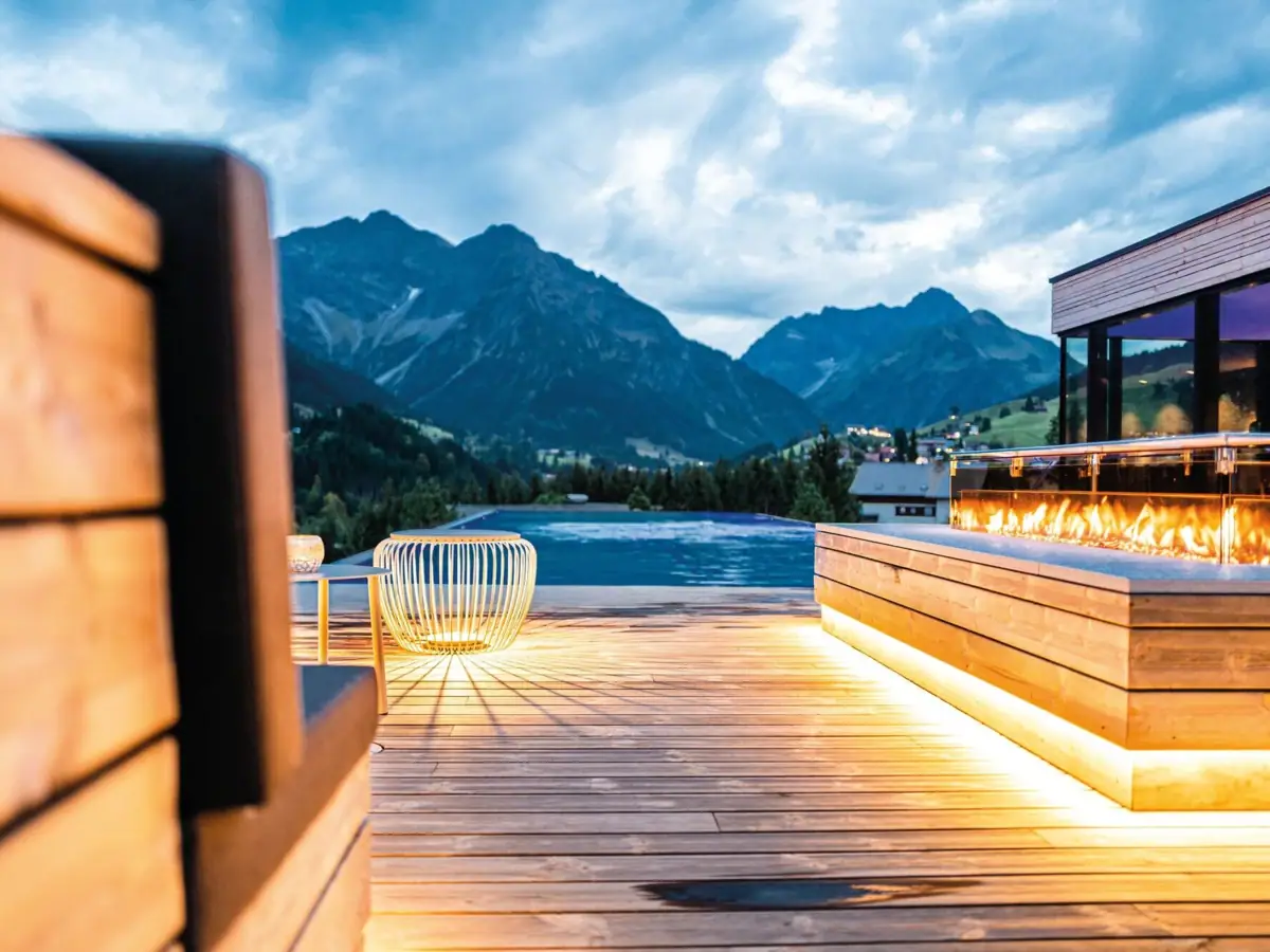 A terrace with a fire and a pool in the background.