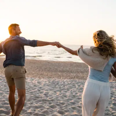 Ein Mann und eine Frau halten Händchen am Strand.