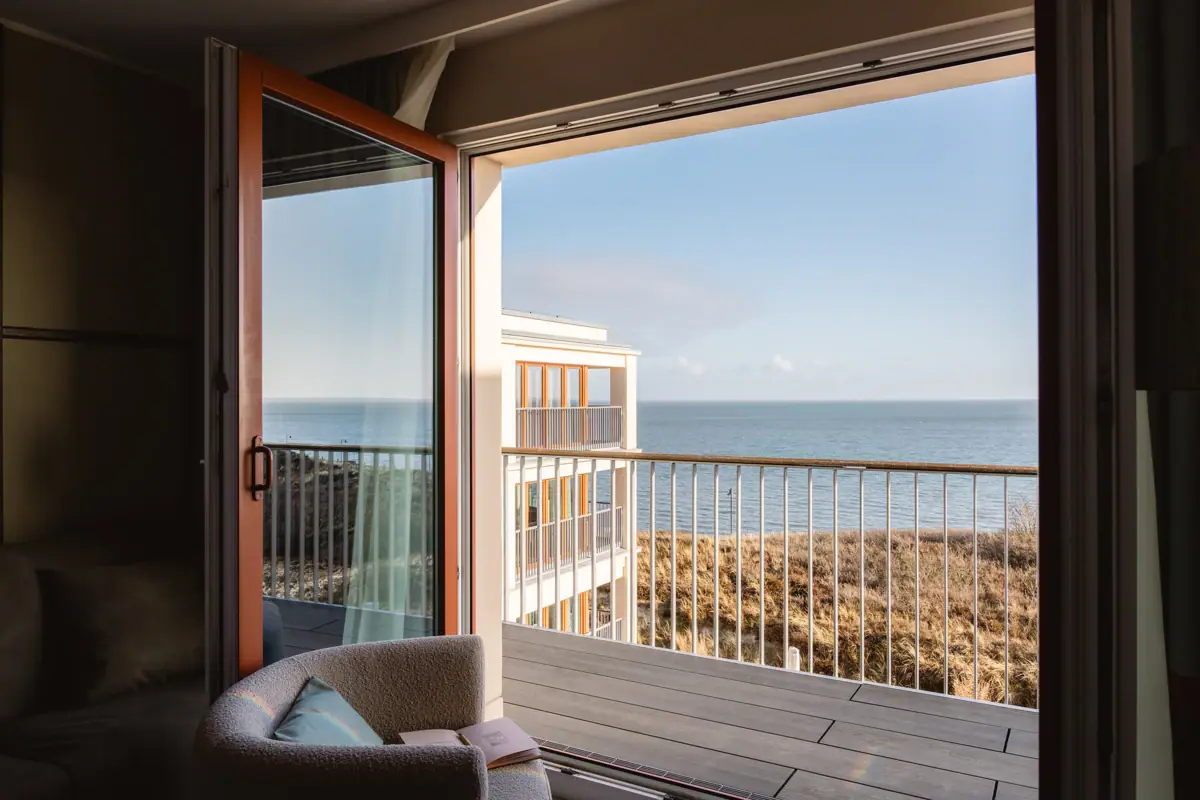 A room with a balcony and a view of the ocean.