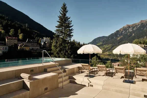 A pool with parasols and deckchairs on a sunny day.