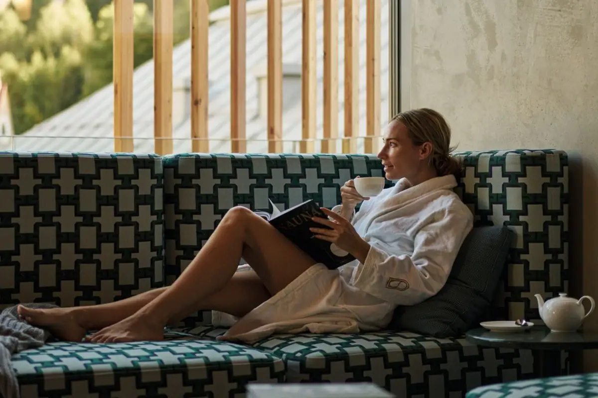 Guest in a bathrobe relaxing with tea and a book in the quiet lounge of the Straubinger Grand Hotel.