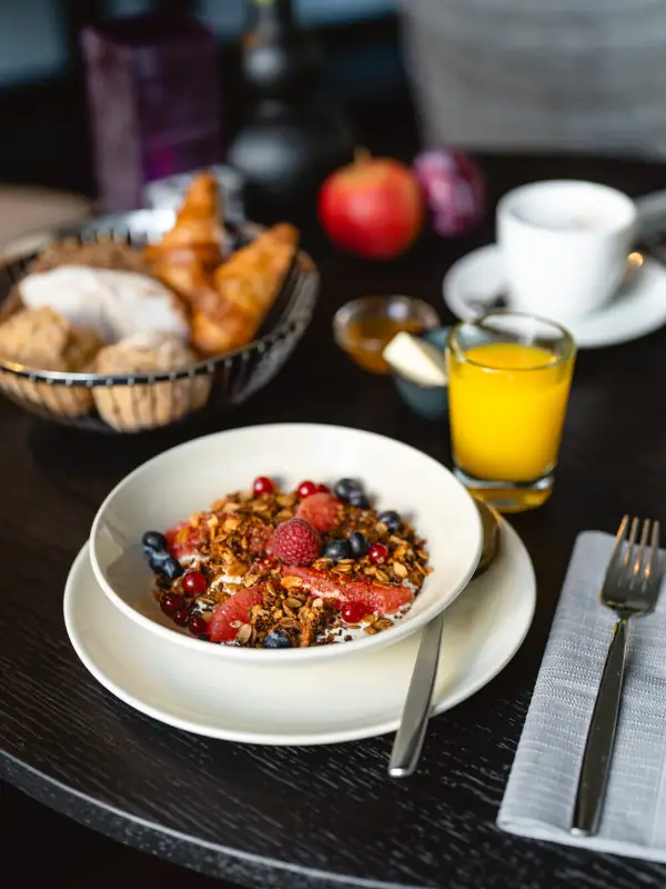 A bowl of fruit and cereal on a table.