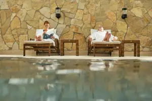 A man and a woman are sitting on sun loungers by the pool.