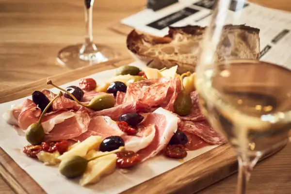 A plate of assorted meats and olives on a table.