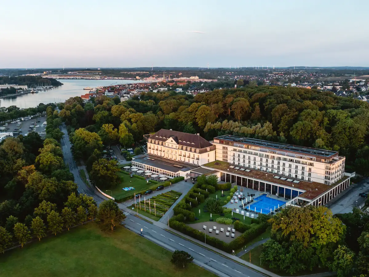 Großes Gebäude mit einem Pool, umgeben von Bäumen.