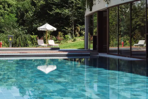 Ein Außenpool mit Pflanzen an der Seite eines Gebäudes.