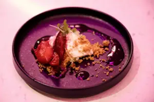 A plate of dessert, garnished with fruit and crumble.