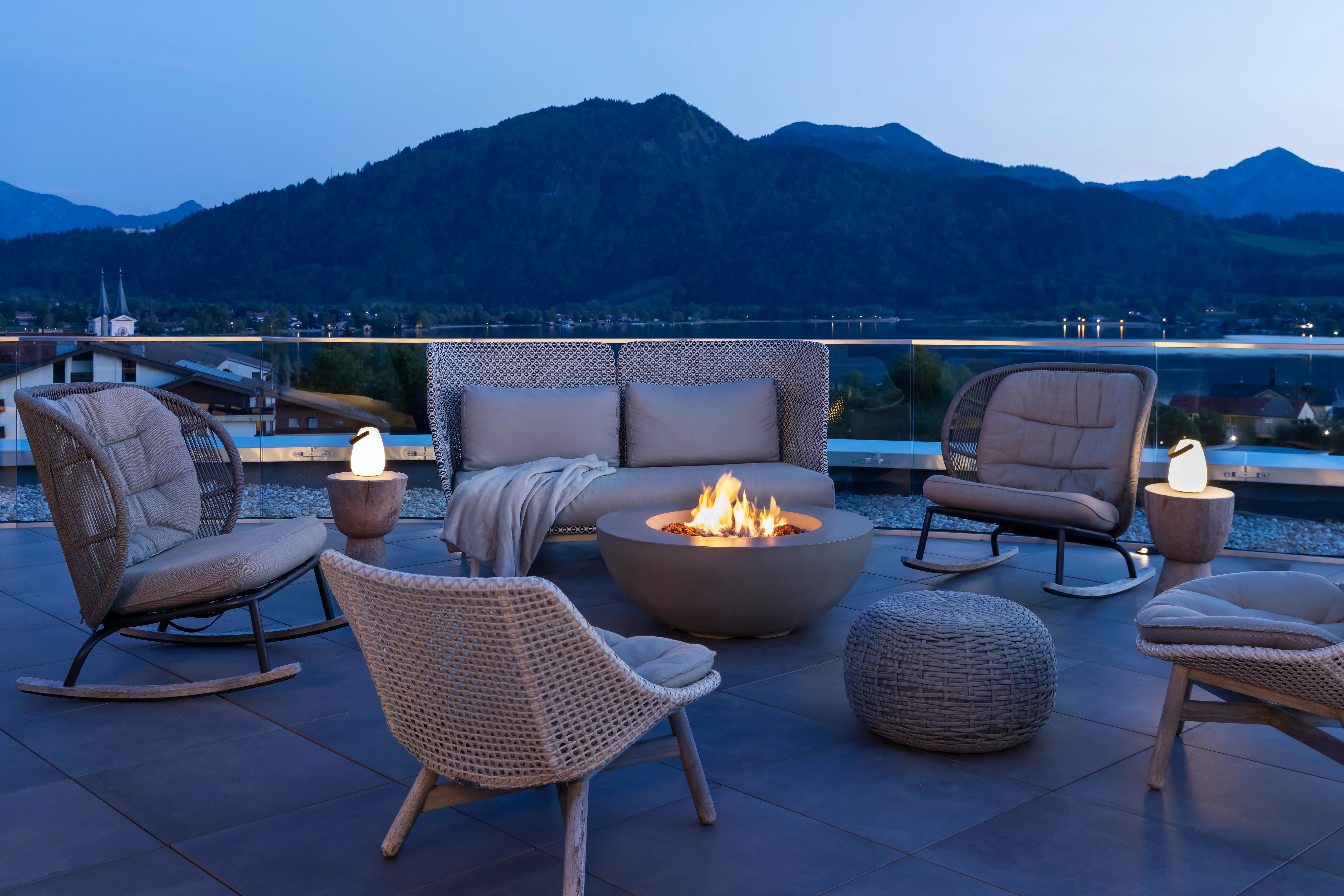 A terrace with a fire pit and chairs on a balcony.