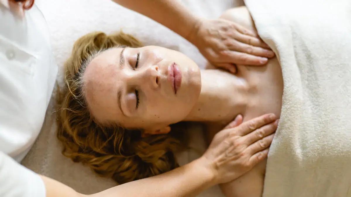Massage A woman receiving a massage indoors, appearing relaxed and comfortable.