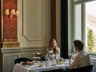 A woman and a man sit at a breakfast table with many different dishes. 