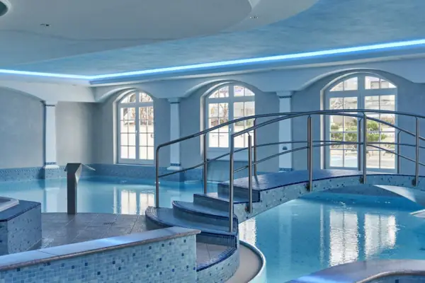 A swimming pool with a curved walkway indoors.