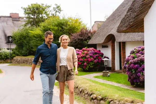 A man and a woman are walking along a street in Kampen on Sylt.