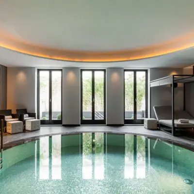 Indoor pool with a bed and a canopy over it.