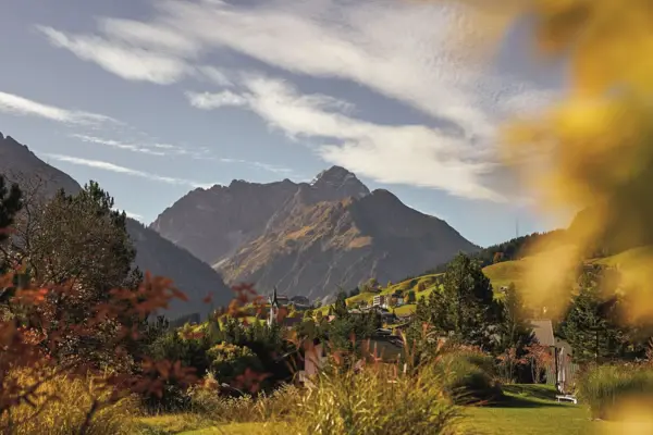 Autumn landscape with a mountain in the background, surrounded by grass and scattered trees.