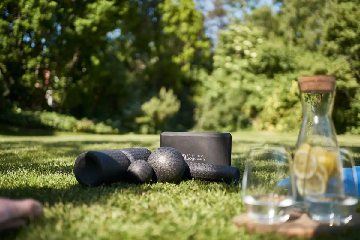 Yoga mats and a glass of water on grass.