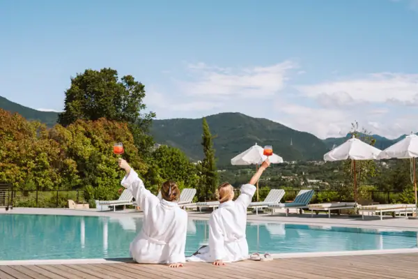 Zwei Personen stoßen mit Aperitivo-Gläsern am Pool des A-ROSA Gardasee an