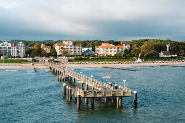 A jetty by the water with the sky and clouds in the background.