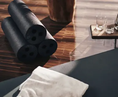 Yoga mats and glasses on a dark wooden floor.