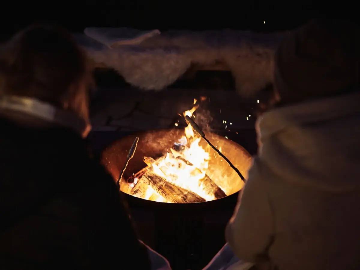 People sitting around a fire pit with visible flames.