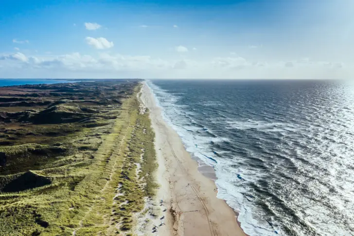 Long beach with waves lapping against the shore.
