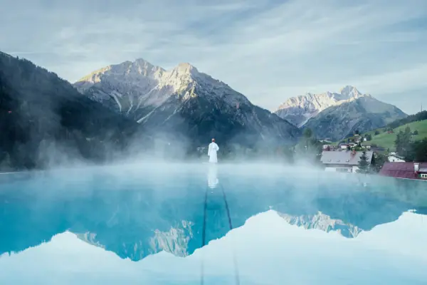 A person by the pool with a mountain landscape in the background