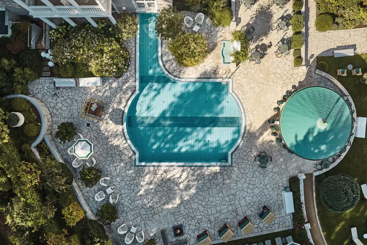 A swimming pool in a backyard with surrounding trees and a house nearby.
