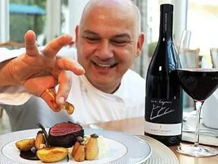 Man holding a piece of meat on a plate.