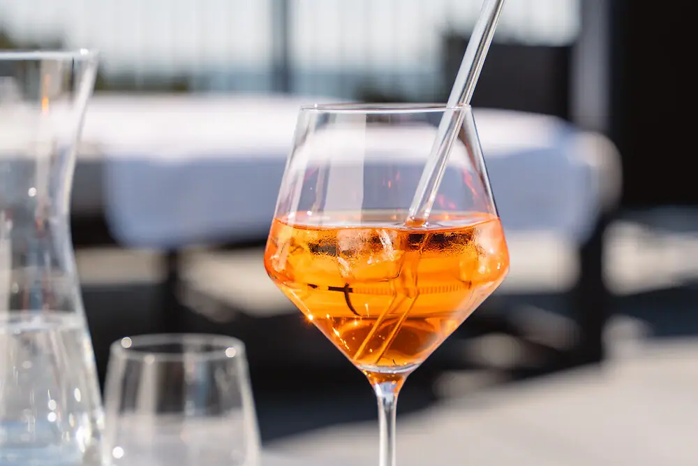 A glass with orange liquid and ice on a table.