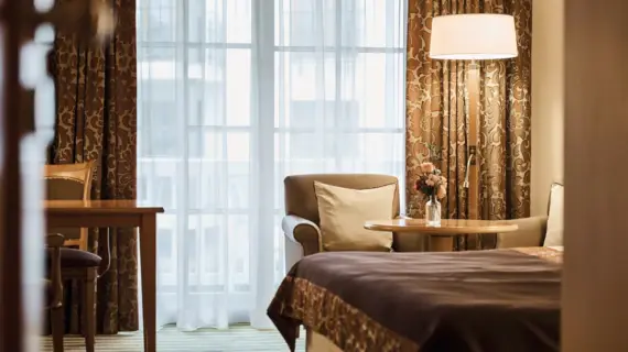 Interior view of a bedroom with a bed, a bedside table and a lamp.